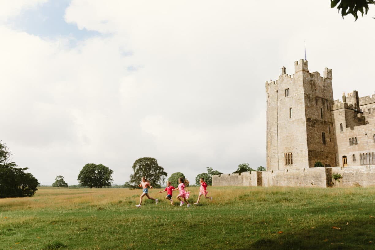 Children and families enjoying immersive activities at Raby Castle, including walking through Wonderland-themed light tunnels, spotting deer in the park, and exploring the castle and gardens with guides.
