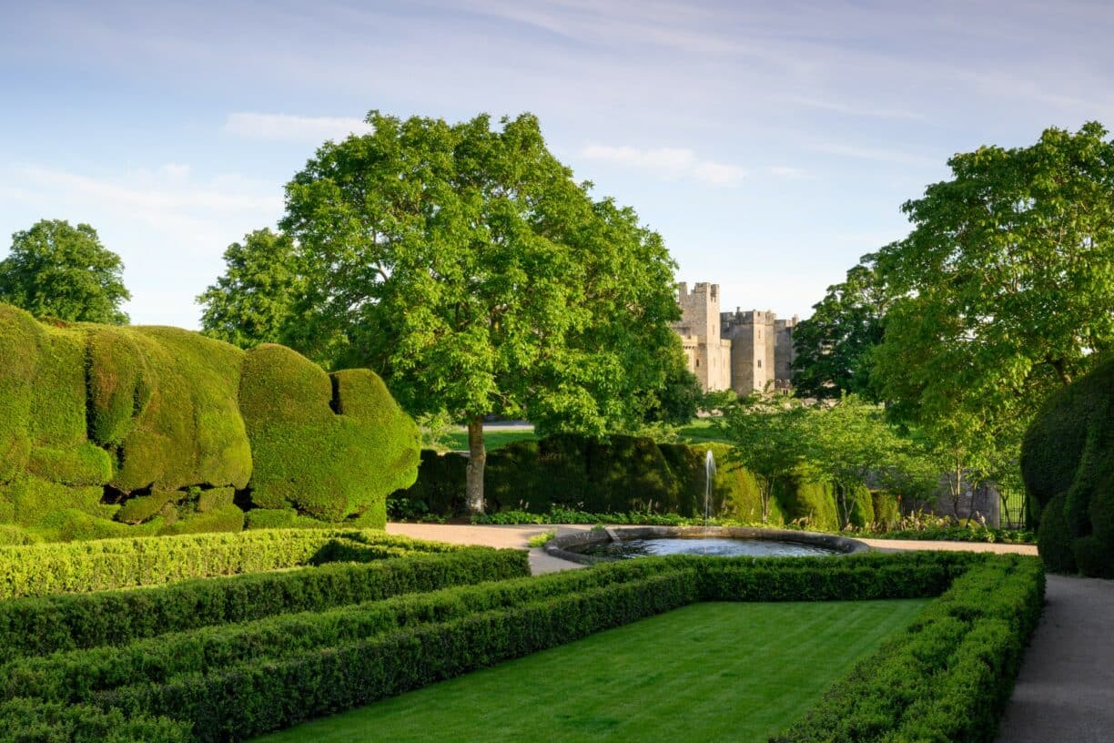 Close-up of a peaceful seating area in Raby Castle’s gardens, surrounded by colourful planting and heritage stonework.