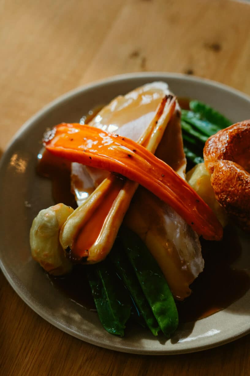 Vegetable Wellington with roast potatoes and seasonal vegetables, served with red pepper sauce